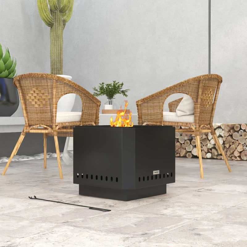 Black square metal fire pit with side vent holes and small flame in outdoor patio