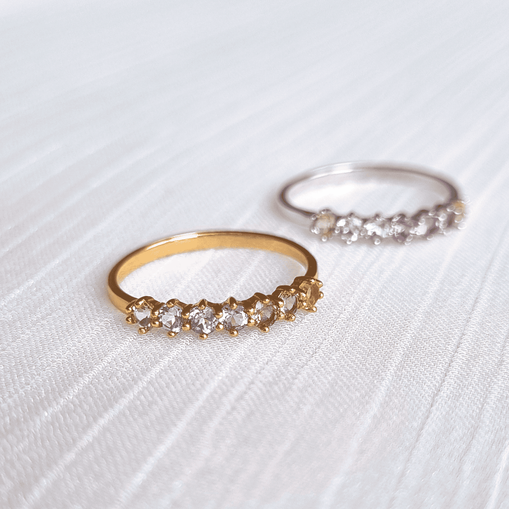 Gold-tone eternity ring with small pastel gemstones, angled view