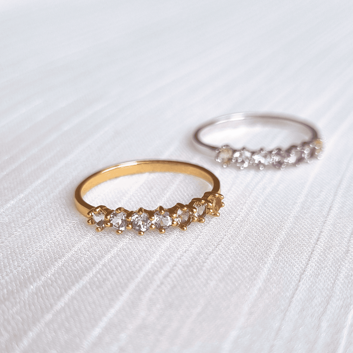 Gold-tone eternity ring with small pastel gemstones, angled view