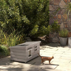 Grey wooden elevated cat house with front windows and openable roof outdoors