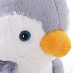 Close-up plush penguin face with orange beak and blue embroidered eye on gray fabric