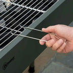 Green charcoal BBQ grill cooking grate with hand using tong to lift a wire section