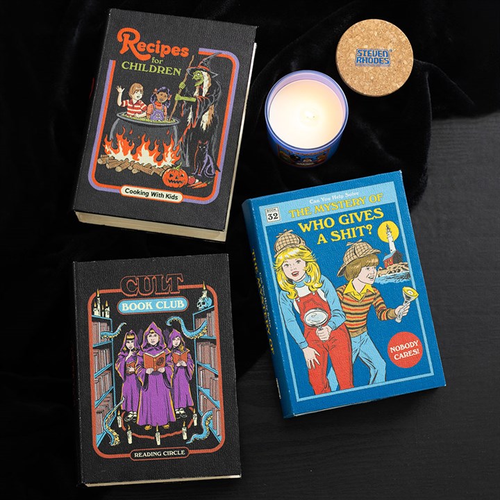 Three books with unique covers on a dark surface next to a candle.