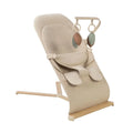 Oatmeal baby bouncer with reclining seat, harness straps, and hanging leaf toy arches