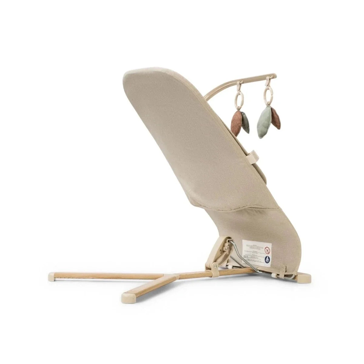 Oatmeal baby bouncer side view with hanging leaf toys and fabric seat on wooden legs