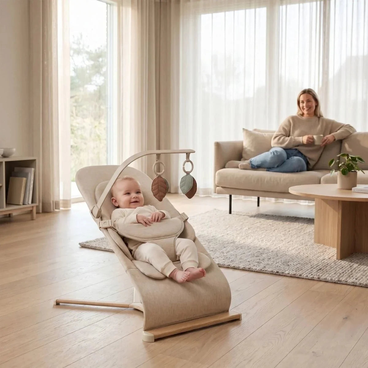 Oatmeal baby bouncer with baby seated, hanging leaf toys