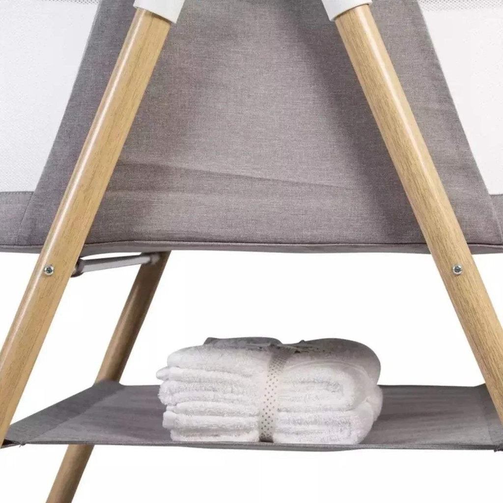 Grey inner bassinet with wooden legs and grey base shelf, folded white blanket.