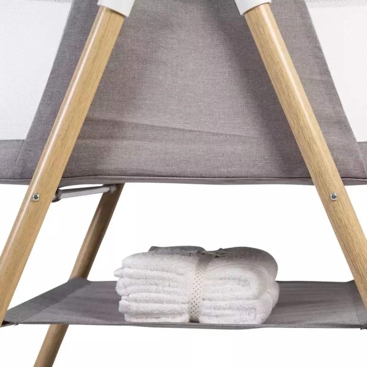 Grey inner bassinet with wooden legs and grey base shelf, folded white blanket.