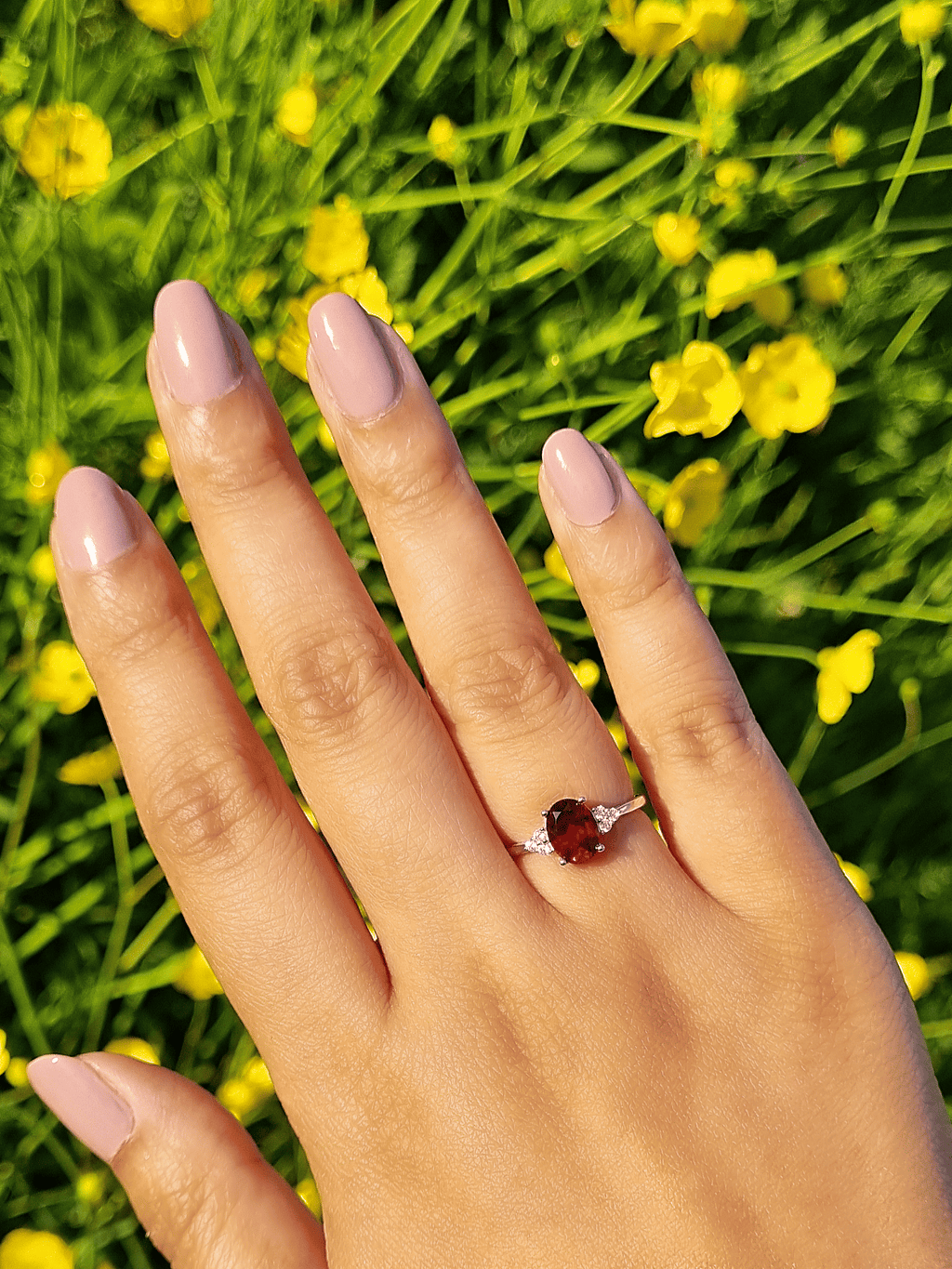 Sterling silver ring with round garnet on a hand