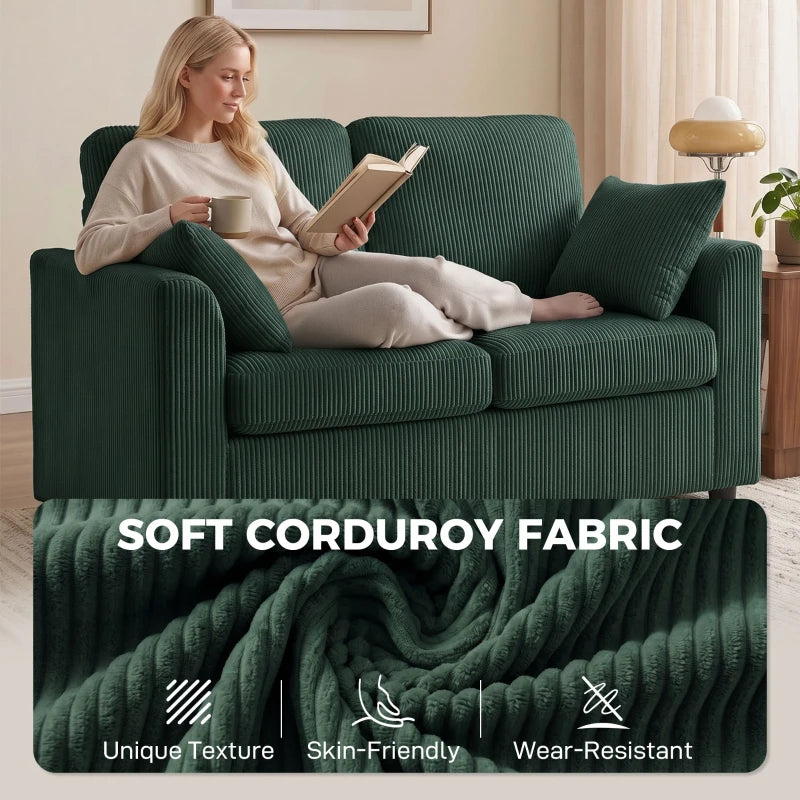 Dark green corduroy 2-seat sofa with two pillows, person lounging and reading