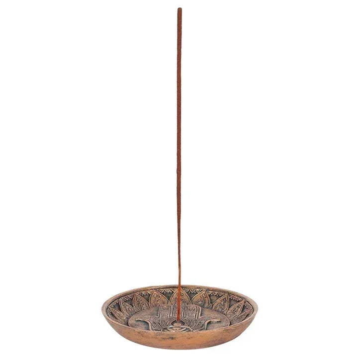 Incense holder plate with Hamsa hand motif and upright incense stick on bronze dish