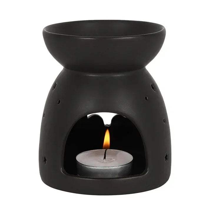 Black oil burner with bat cut-out and lit tealight visible inside