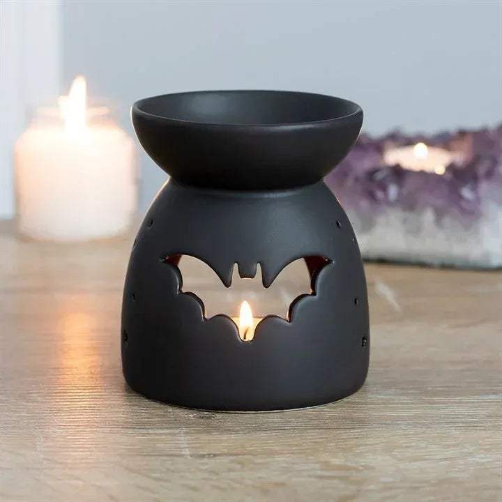 Black bat cut-out oil burner with flame visible through front cutout