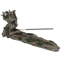 Gray resin incense stick holder shaped as a reclining tree spirit with green leaf accents