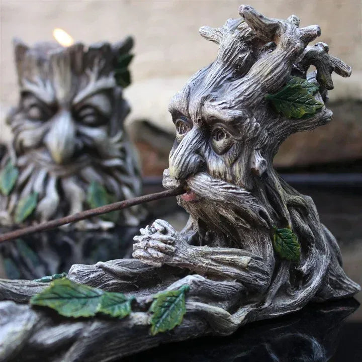 Close-up gray resin incense stick holder: tree spirit face and hands with green leaf details