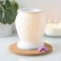 White ceramic electric wax warmer with embossed snowflakes, on cork base