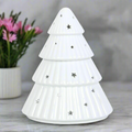 White ceramic pine tree with star decorations on a gray surface with a blurred background