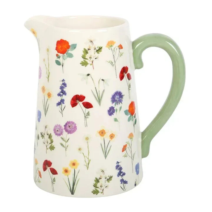 Ceramic flower jug with cream body, green handle, and scattered wildflower flowers