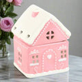 Pink and white gingerbread house oil burner with heart door and chimney cover.
