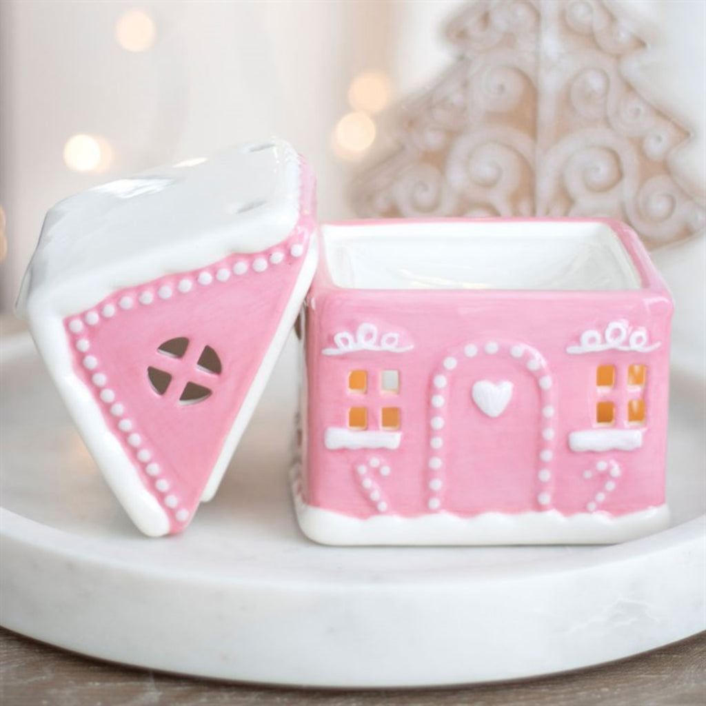 Pink gingerbread house-shaped container with a white lid on a light background