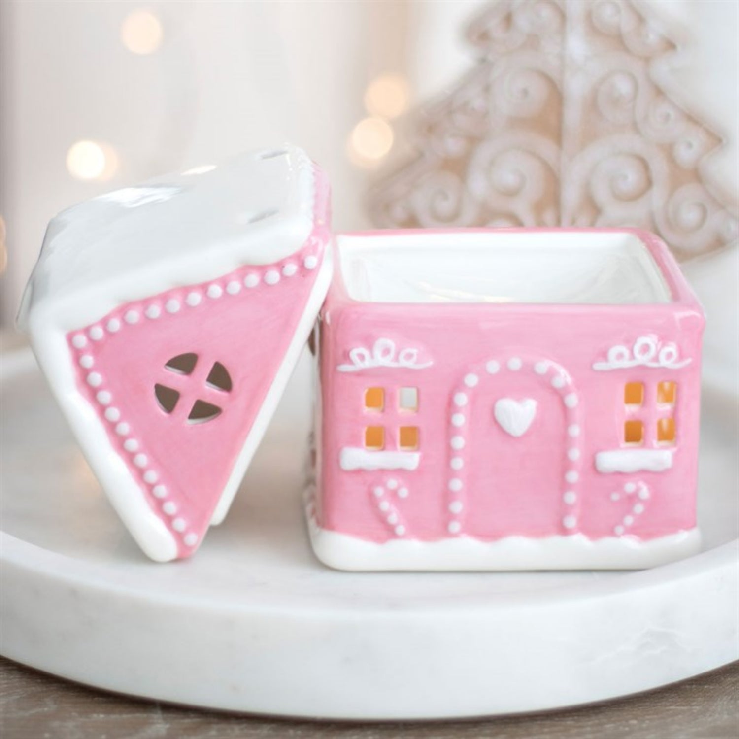 Pink gingerbread house-shaped container with a white lid on a light background