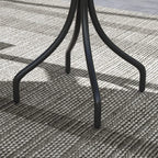 Detail of black curved pedestal legs with table supported over outdoor rug.