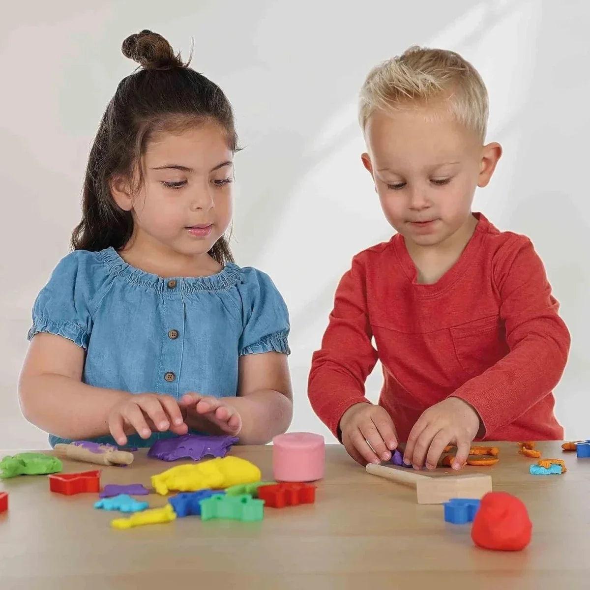 Children playing with colorful sparkle dough on a tabletop with cut-out shapes