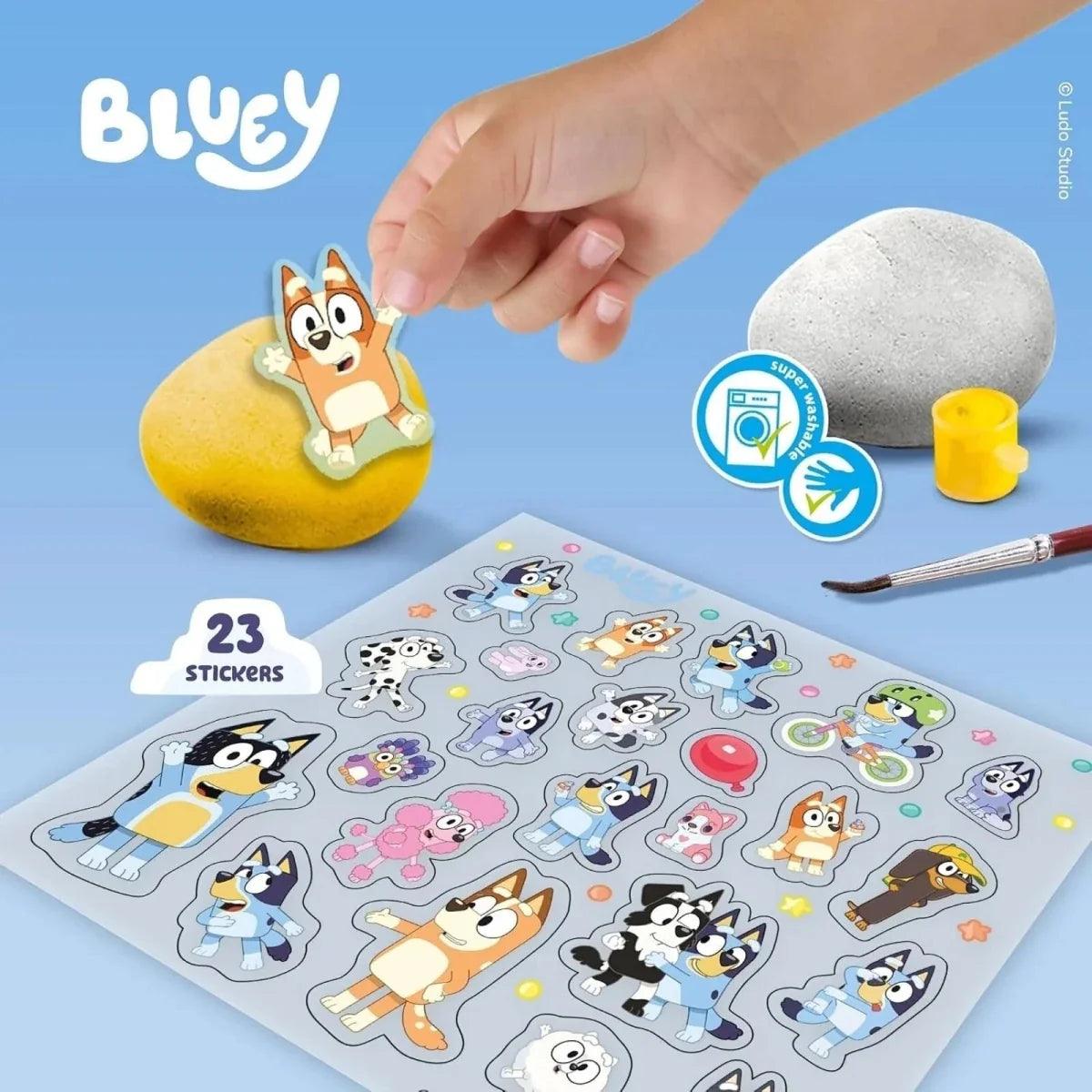 Rock painting kit: hand painting a stone with brush, paint pots, and sticker sheet