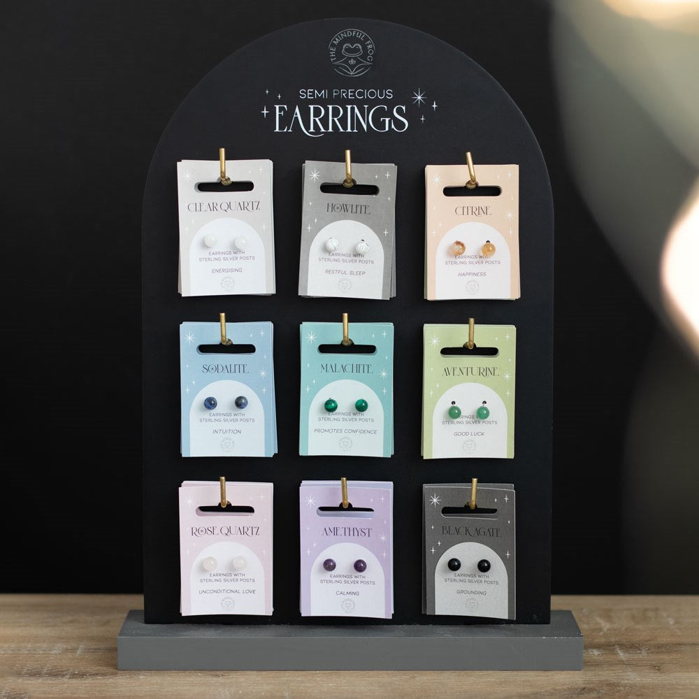 Display stand with packages of semi-precious earrings on a wooden surface.