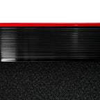 Close-up of black treadmill running belt with red stripe on the deck edge