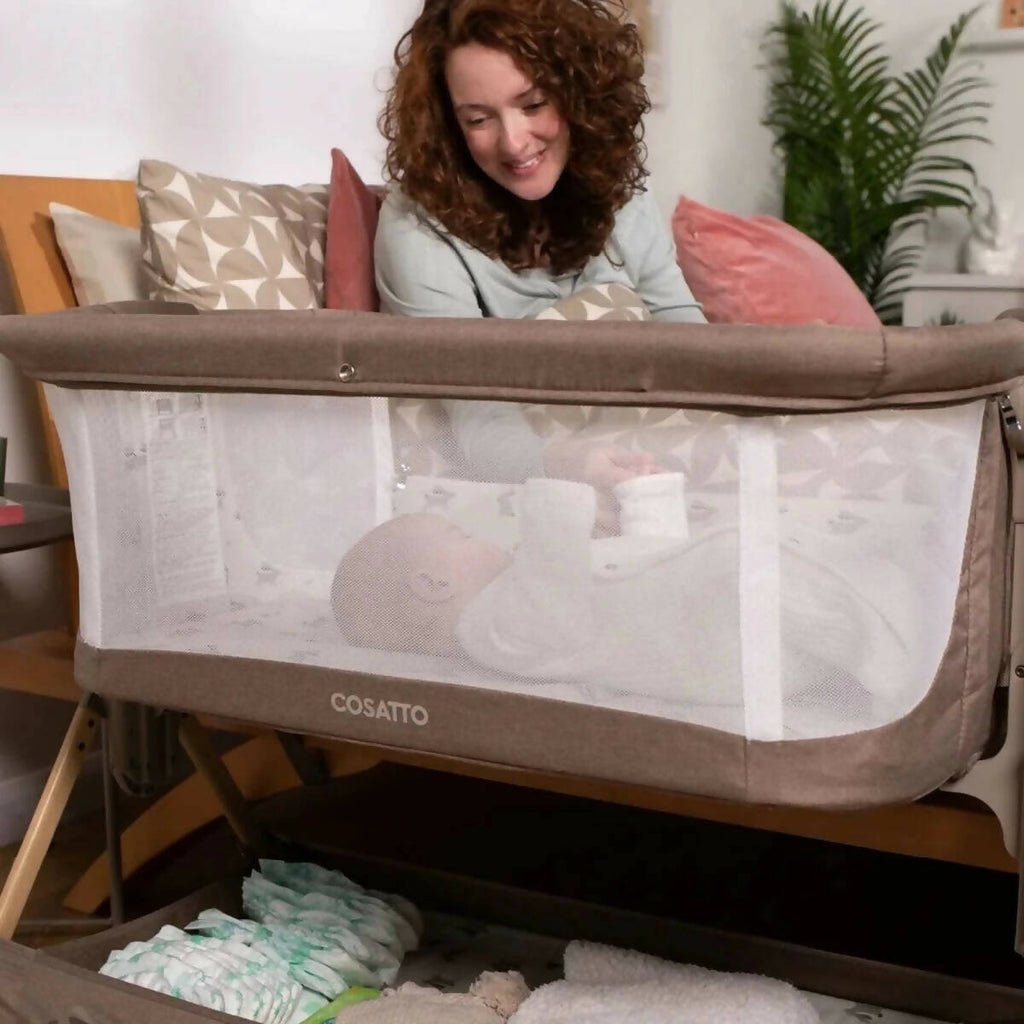 Olive and white folding bedside crib with mesh side panels and patterned mattress base