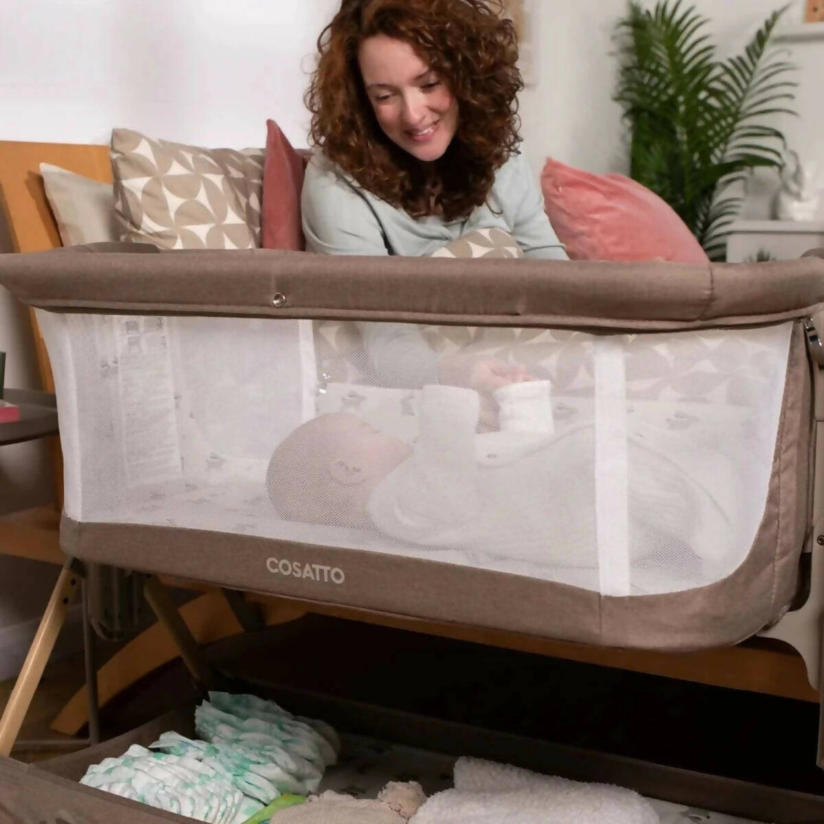 Olive and white folding bedside crib with mesh side panels and patterned mattress base
