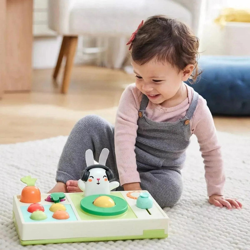 Toddler playing with bunny DJ music toy with light-up vegetable controls on base