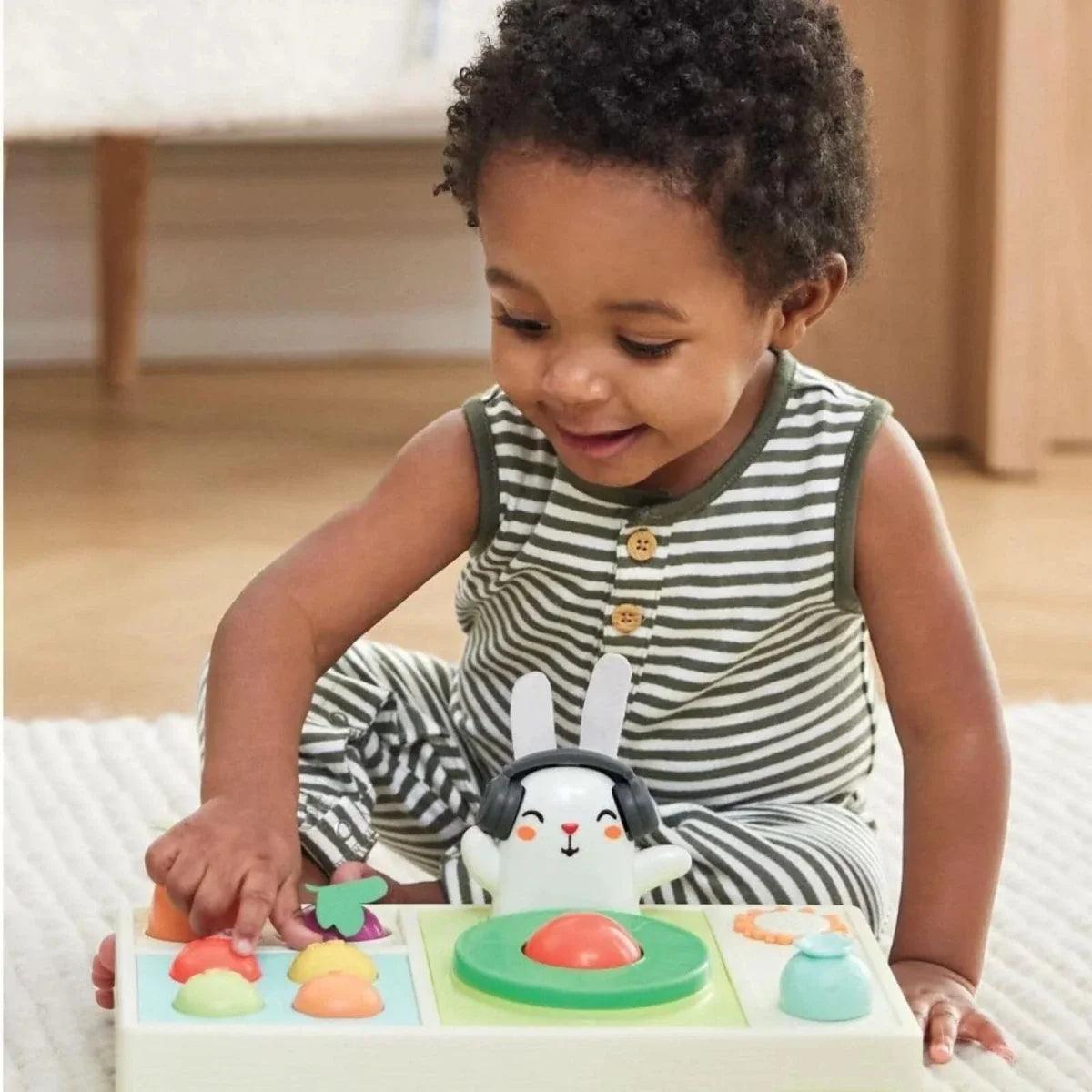 Young child pressing vegetable buttons on bunny DJ music toy with green turntable