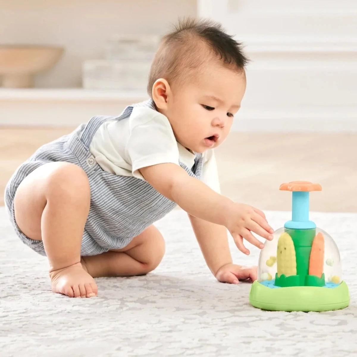 Crawling baby pushing push-and-spin walker toy with green base and blue post