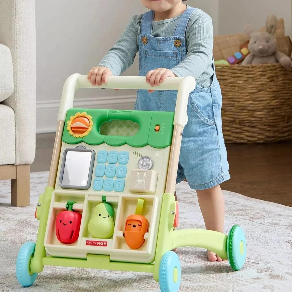 Toddler standing with green push walker, front panel with fruit-shaped toys