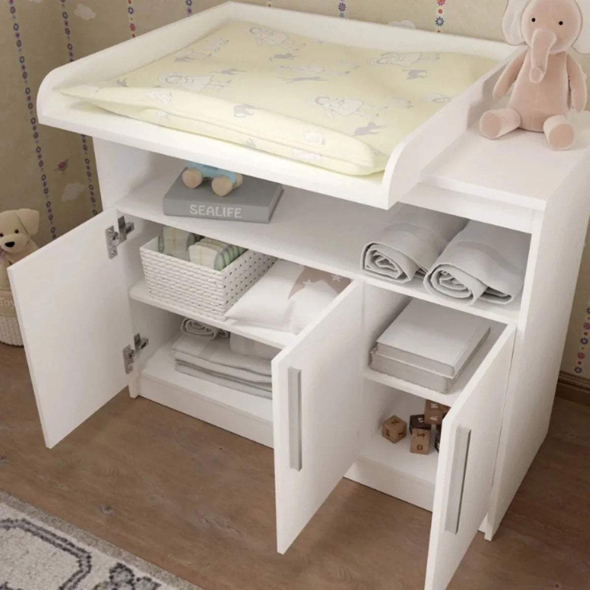 White kids changing unit with open shelves, folded liners, and changing pad