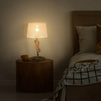 Beige fabric-shade table lamp with twisted rope stem and lit lightbulb