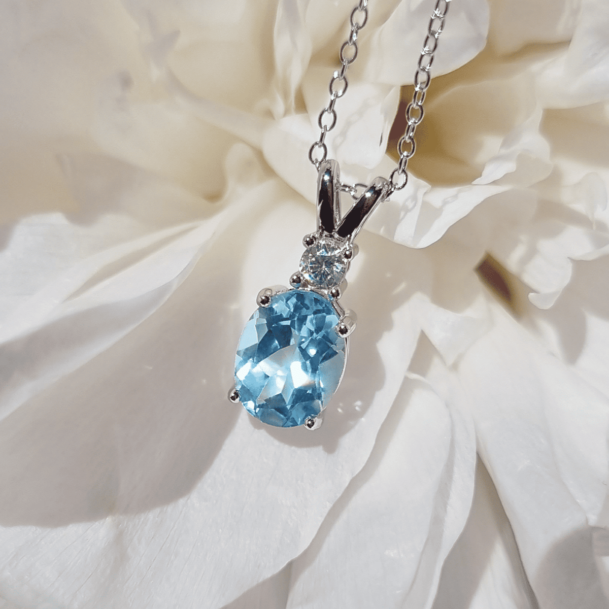 Sterling silver blue topaz pendant necklace on link chain with crown setting and oval stone