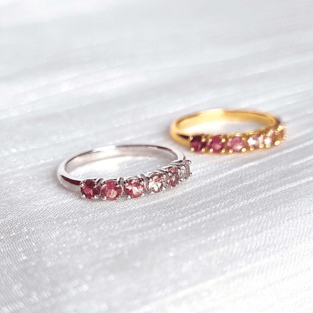 Silver eternity band with pink oval gemstones and small clear stones along the row