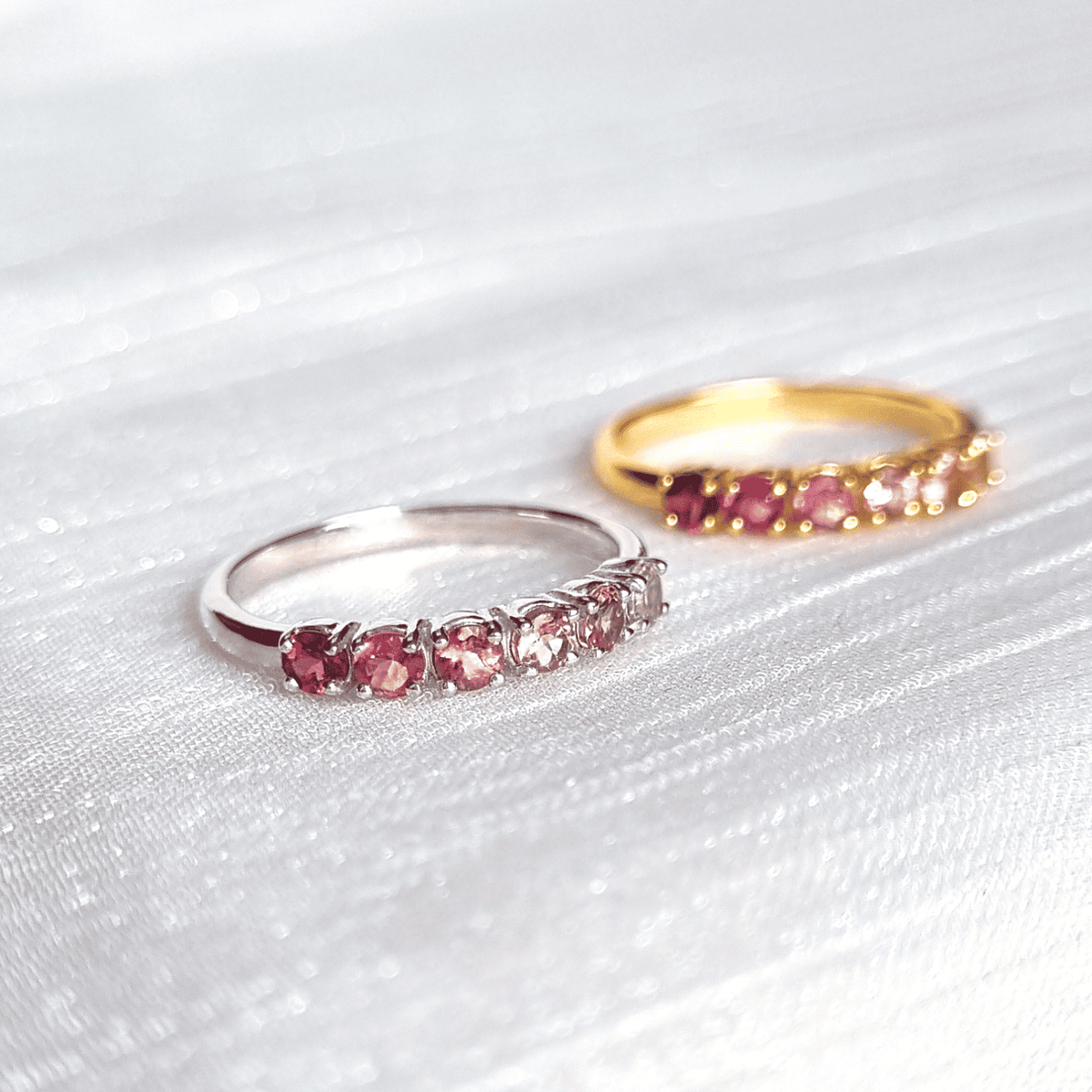 Silver eternity band with pink oval gemstones and small clear stones along the row