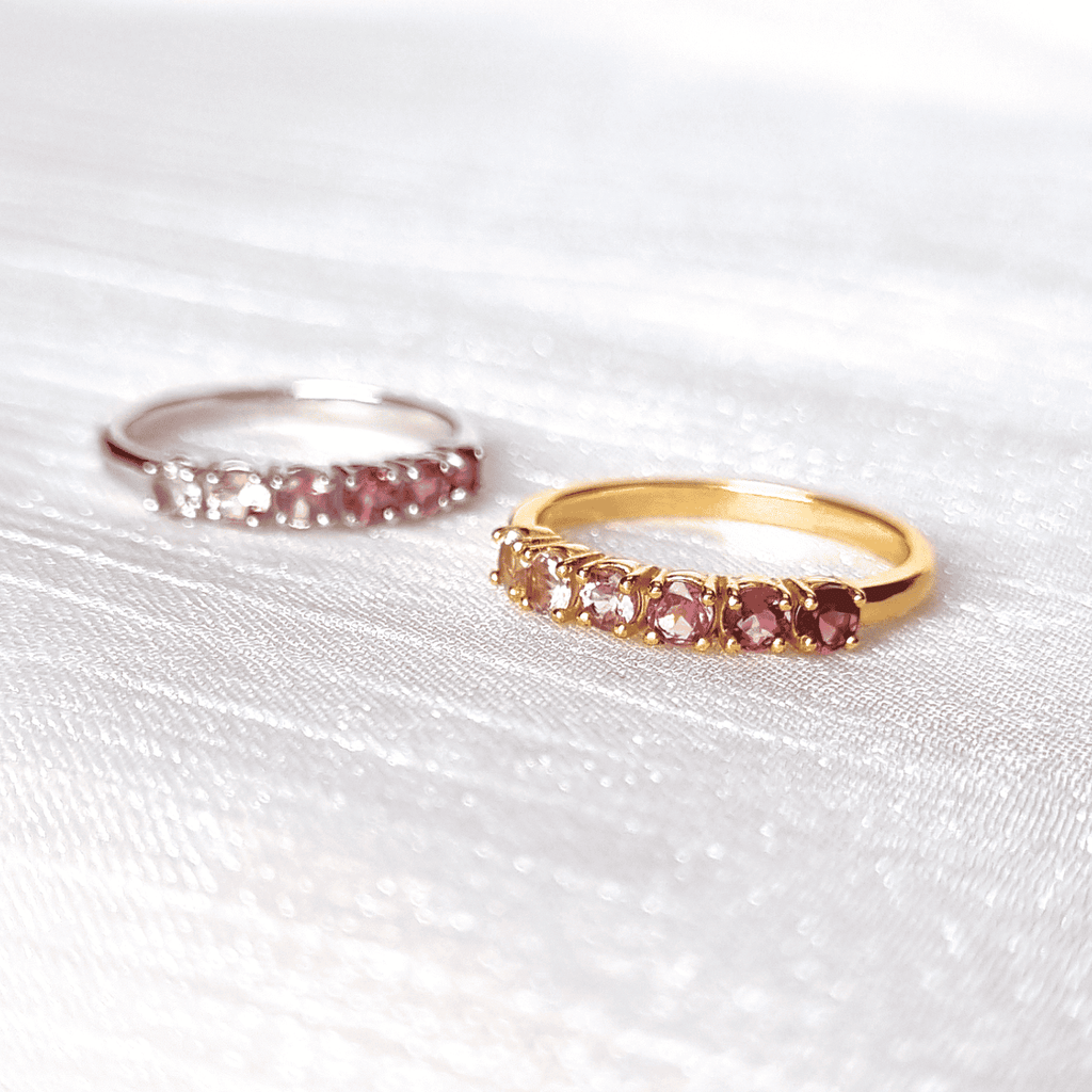 Gold and silver eternity bands with pink tourmaline stones on fabric