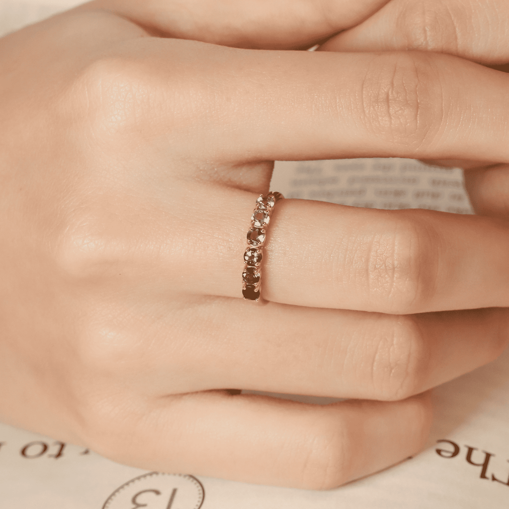 Gold-tone slim eternity ring with a row of small green stones