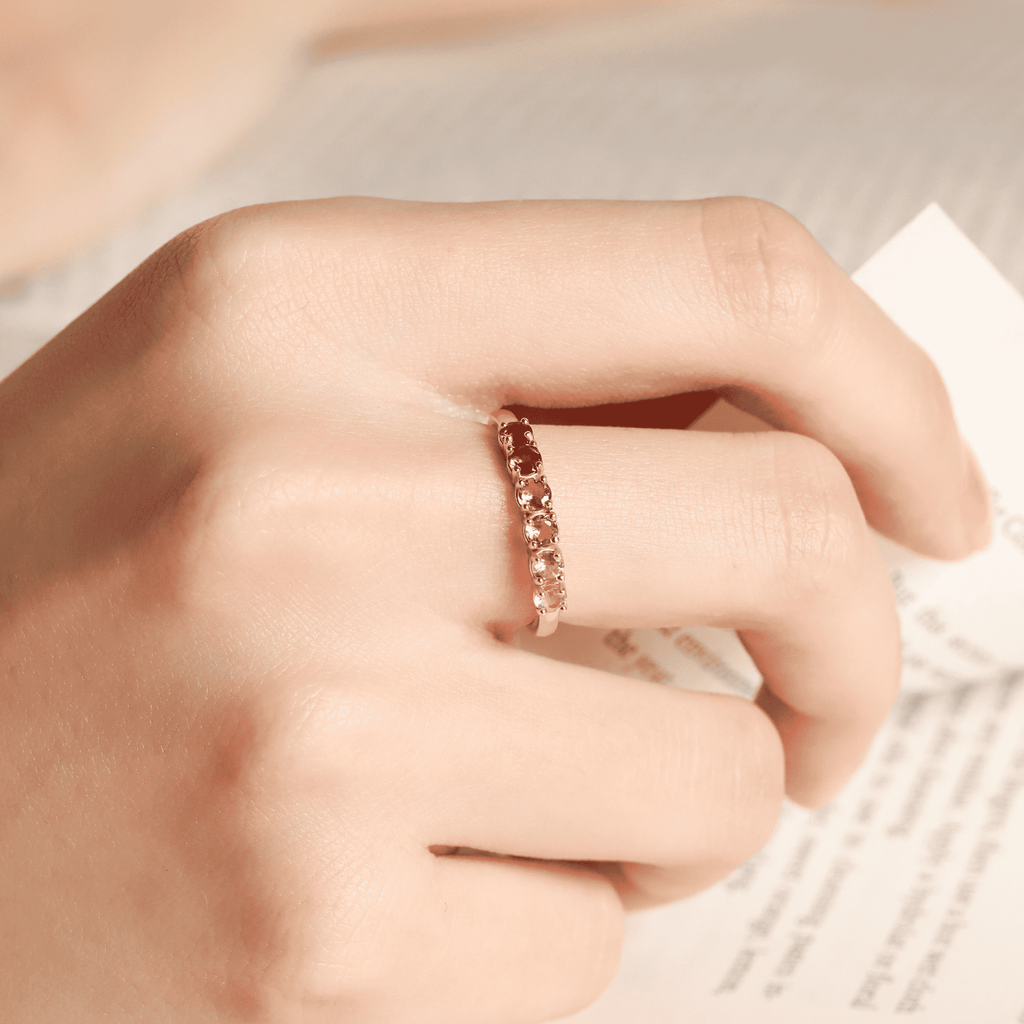 Rose-toned tourmaline eternity band on finger with small prong-set stones