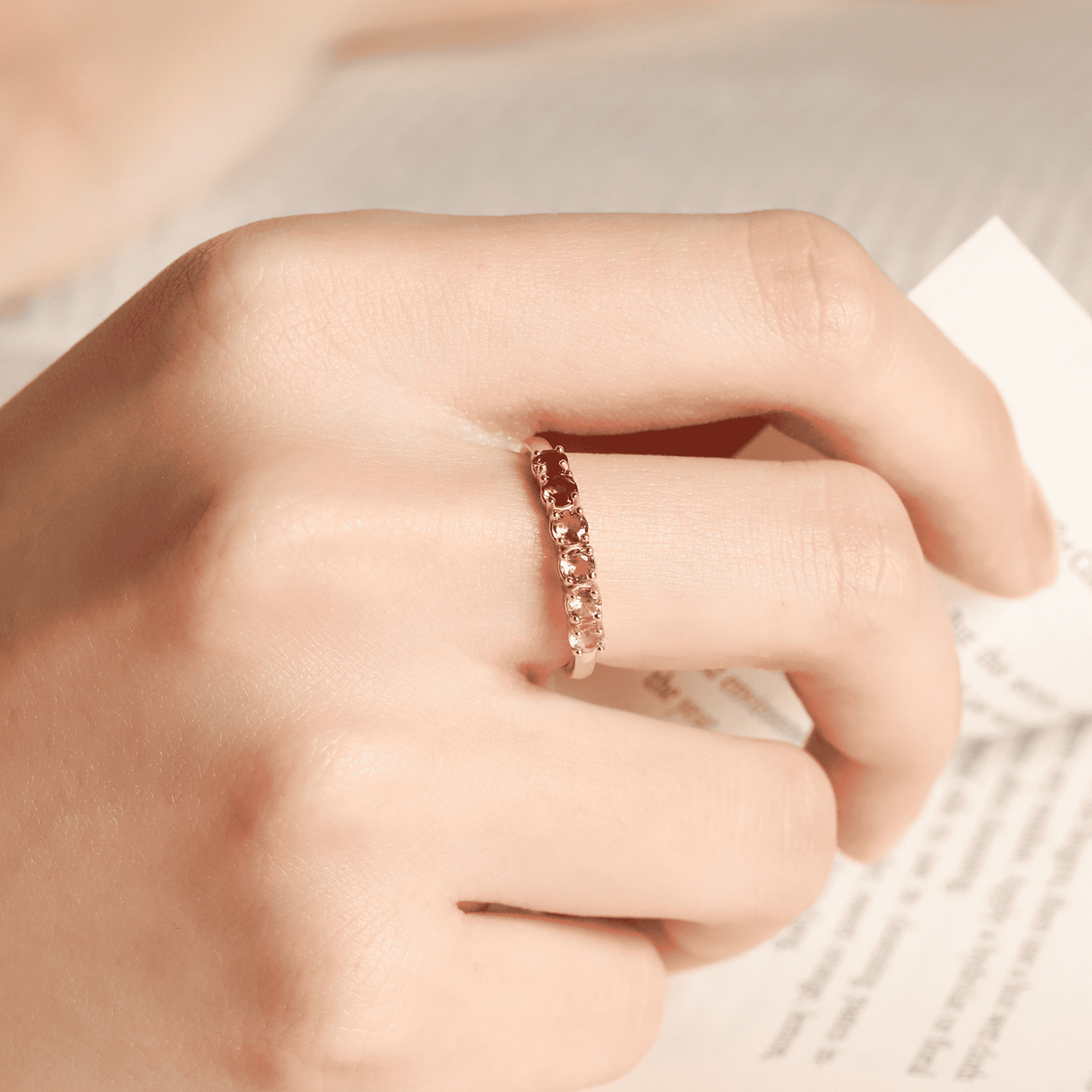Rose-toned tourmaline eternity band on finger with small prong-set stones