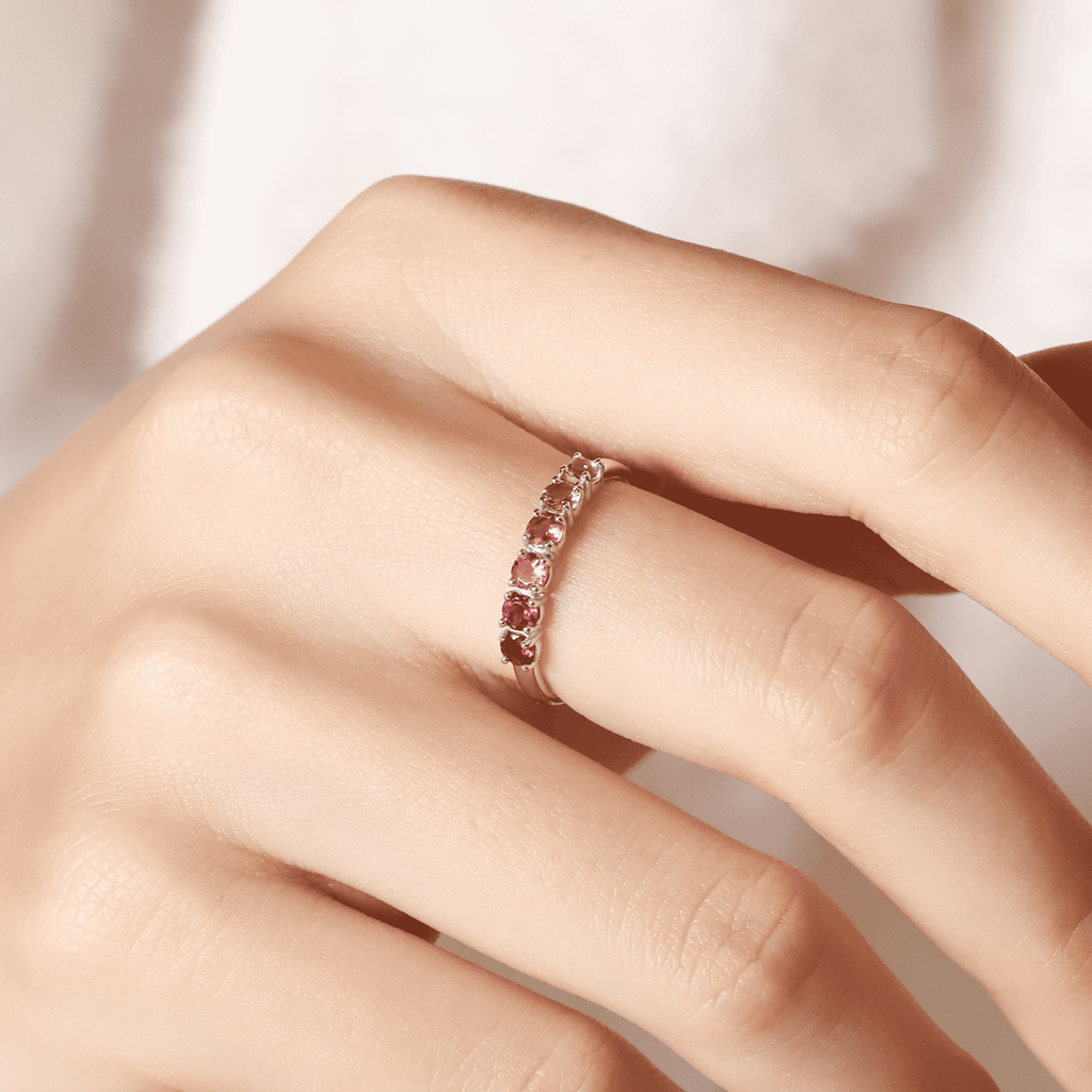 Pink gemstone eternity band on finger, with repeating oval stone settings