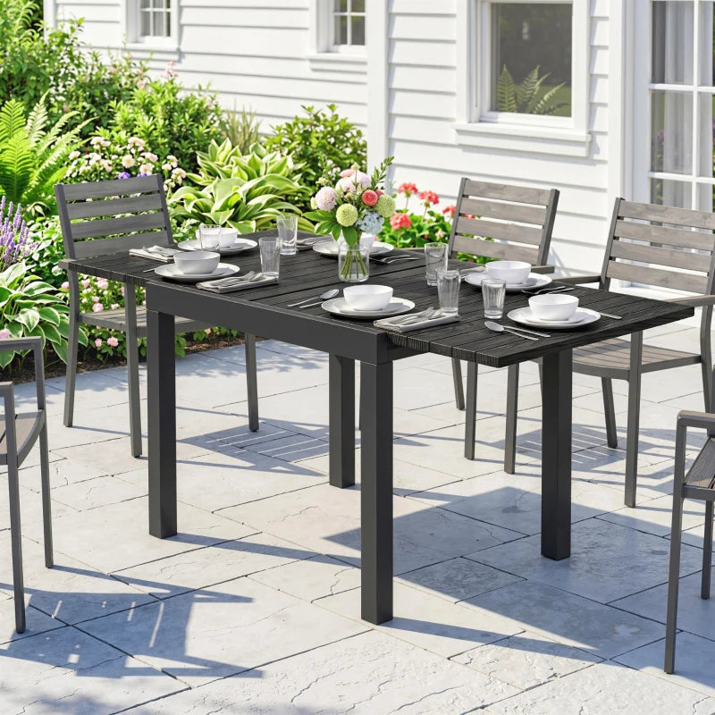 Black outdoor extending dining table with slatted top and matching chairs on patio