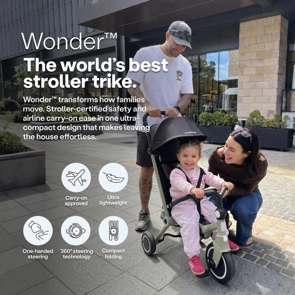 Olive stroller trike with black canopy and safety bar, positioned outdoors with riders