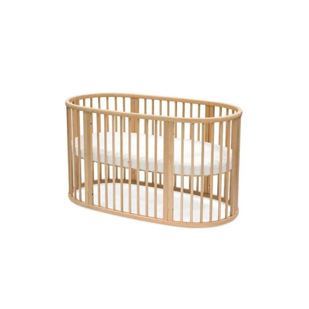 Natural wood oval baby crib side view with vertical slat rails and curved frame