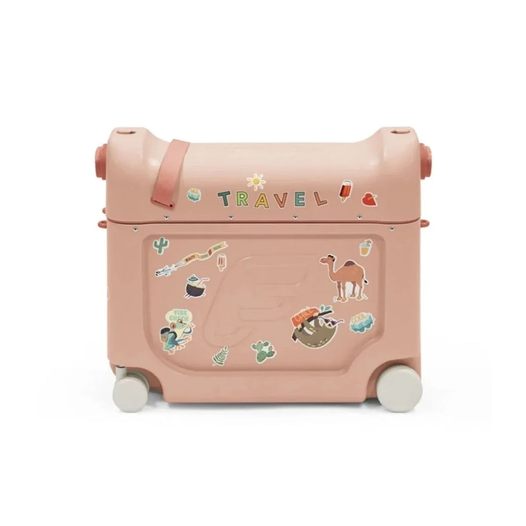 Coral pink BedBox ride-on suitcase with travel sticker scene, front latch, and wheels